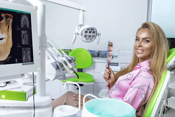 Beautiful happy woman sitting in the dental chair and enjoying her new smile. Porcelain veneers. Teeth whitening.