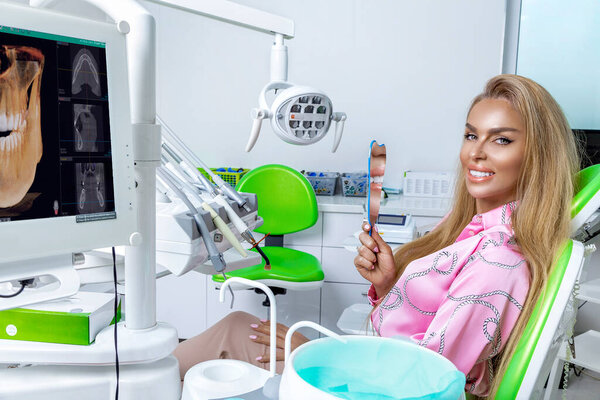 Beautiful happy woman sitting in the dental chair and enjoying her new smile. Porcelain veneers. Teeth whitening.