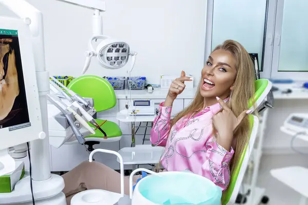 Beautiful happy woman sitting in the dental chair and enjoying her new smile. Porcelain veneers. Teeth whitening.