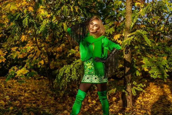 Zarif sonbahar kış kıyafetleri, şık aksesuarlar ve yeşil fular giyen güzel bir kadın model güneşli bir günde parkta poz veriyor..