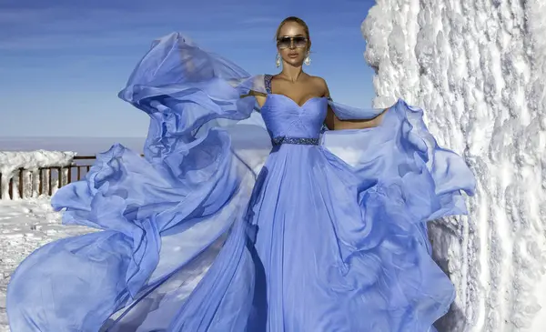 美丽优雅的女人穿着蓝色飘逸的长裙 在一个阳光明媚的山里摆姿势 白雪公主 图库图片