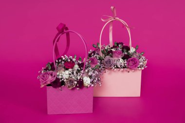 Çiçekli şık bir çanta. Pembe arka planda bahar çiçekleri olan hediye kutusu. Çiçekçi kavramı.