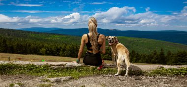 Şirin köpekli güzel bayan yürüyüşçü dev dağın eteklerine hayran kalıyor. Dev Dağlar, Polonya.