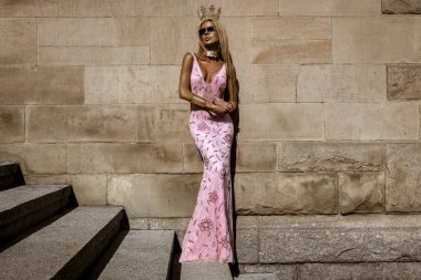 Şık lüks akşam modası. Cazibeli, şık, zarif, uzun gece elbisesi giymiş bir kadın şehirde poz veriyor. Muhteşem uzun elbiseli kadın model. Açık hava çekimi. Vogue. Özel tasarım.