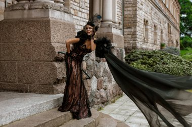 Şık lüks akşam modası. Şato bahçesinde poz veren siyah dantelli, şık, zarif bir kadın. Muhteşem uzun elbiseli bir model. Açık hava seansı. Vogue. Özel tasarım.