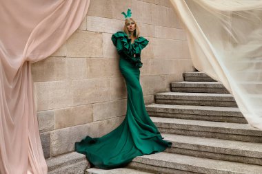 Şık lüks akşam modası. Cazibeli, zarif, yeşil uzun gece elbisesi giymiş kadın açık havada poz veriyor. Muhteşem uzun elbiseli kadın model. Açık hava çekimi. Vogue. Özel tasarım.