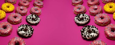 Tasty donuts with pink, yellow, and white icing, topped with colorful sprinkles, stacked against a bold pink background. A sweet and visually striking composition full of flavor. clipart