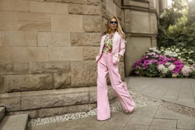 Zarif pembe takım elbiseli ve çiçekli gömlekli güzel bir kadın güneşli bir yaz gününde şehrimizde şehvetle dolaşıyor. Lüks yaz modası