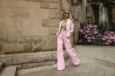 Zarif pembe takım elbiseli ve çiçekli gömlekli güzel bir kadın güneşli bir yaz gününde şehrimizde şehvetle dolaşıyor. Lüks yaz modası