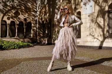 Şık Bej Elbiseli Moda Modeli ve Yaz Güneşi 'nde Şık Motosiklet Ceketi Pozu. Yaz Kentsel Moda.