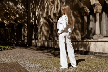 Güzel ve zarif bir kadın. Beyaz, şık bir takım elbise giymiş. Şehrimizde şehvetli bir şekilde dolaşıyor. Zarafet. İş kadını bakışı.