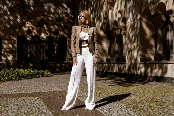 Güzel ve zarif bir kadın. Beyaz, şık bir takım elbise giymiş. Şehrimizde şehvetli bir şekilde dolaşıyor. Zarafet. İş kadını bakışı.