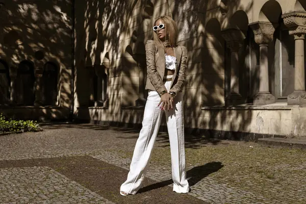 Güzel ve zarif bir kadın. Beyaz, şık bir takım elbise giymiş. Şehrimizde şehvetli bir şekilde dolaşıyor. Zarafet. İş kadını bakışı.