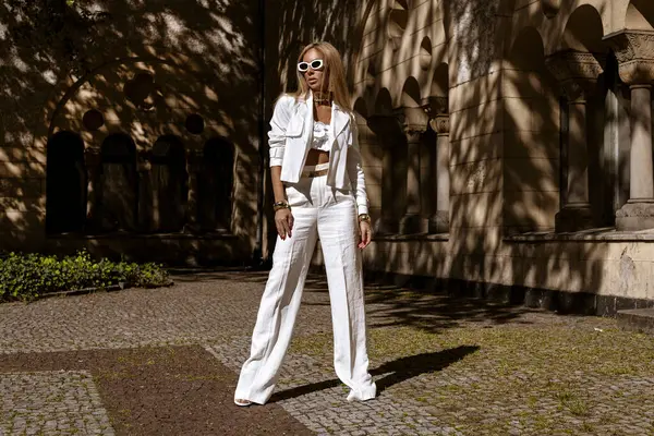 Güzel ve zarif bir kadın. Beyaz, şık bir takım elbise giymiş. Şehrimizde şehvetli bir şekilde dolaşıyor. Zarafet. İş kadını bakışı.