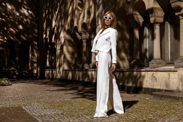 Güzel ve zarif bir kadın. Beyaz, şık bir takım elbise giymiş. Şehrimizde şehvetli bir şekilde dolaşıyor. Zarafet. İş kadını bakışı.