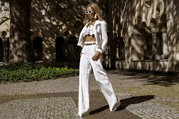 Güzel ve zarif bir kadın. Beyaz, şık bir takım elbise giymiş. Şehrimizde şehvetli bir şekilde dolaşıyor. Zarafet. İş kadını bakışı.