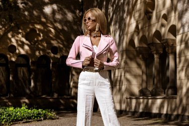 Güzel ve zarif bir kadın klasik beyaz takım elbiseli güneşli bir yaz gününde şehrimizde şehvetle dolaşıyor. Zarafet. İş kadını bakışı.