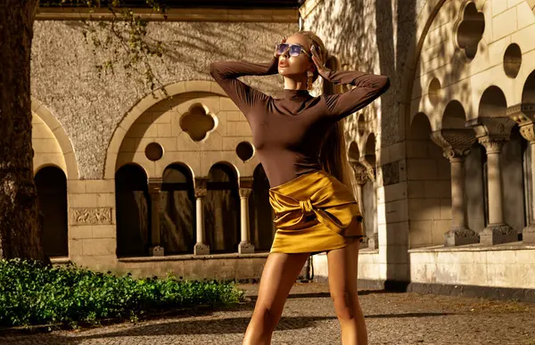 Şık yaz elbisesi içinde uzun sarı saçlı güzel kadın manken güneşli bir yaz gününde şehirde şehvetli pozlar veriyor. Yaz Moda..