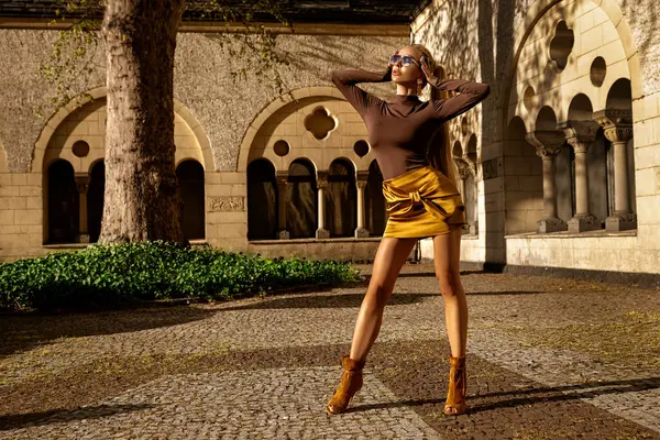 Şık yaz elbisesi içinde uzun sarı saçlı güzel kadın manken güneşli bir yaz gününde şehirde şehvetli pozlar veriyor. Yaz Moda..