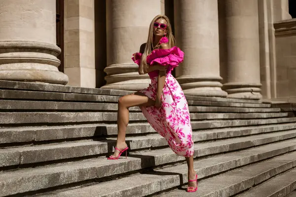 Pembe çiçekli yaz eteği ve şık fırfırlı bluzla şık, şık bir model güneşli bir yaz gününde şehrimizde şehvetli bir şekilde dolaşıyor. Açık havada fotoşop.