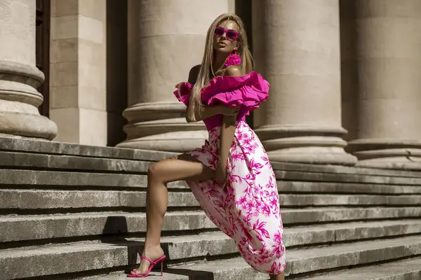 Pembe çiçekli yaz eteği ve şık fırfırlı bluzla şık, şık bir model güneşli bir yaz gününde şehrimizde şehvetli bir şekilde dolaşıyor. Açık havada fotoşop.