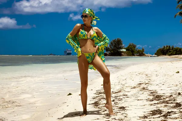 Tropikal yeşil bikinili ve eşarplı seksi manken Seyşeller 'deki güneşli kumlu kumlu sahilde poz veriyor.