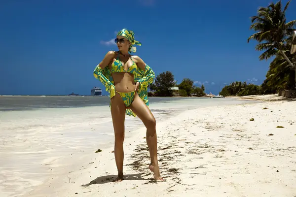 Tropikal yeşil bikinili ve eşarplı seksi manken Seyşeller 'deki güneşli kumlu kumlu sahilde poz veriyor.