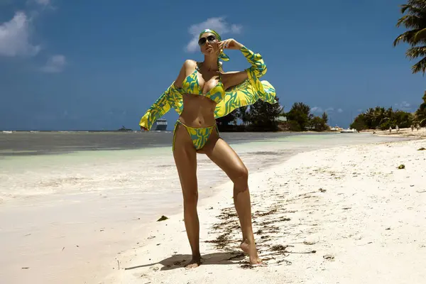 Tropikal yeşil bikinili ve eşarplı seksi manken Seyşeller 'deki güneşli kumlu kumlu sahilde poz veriyor.