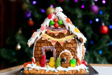 Ev yapımı zencefilli ev krema, şeker ve arka planda bulanık Noel ağacıyla süslenmiş jöleli şekerler. Aile Noeli