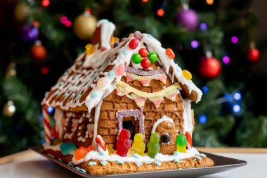 Ev yapımı zencefilli ev krema, şeker ve arka planda bulanık Noel ağacıyla süslenmiş jöleli şekerler. Aile Noeli