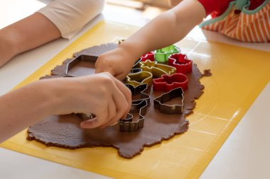 Seçici odaklanma. Çocuklar çeşitli Noel kurabiyeleriyle zencefilli kurabiye yapıyorlar. Zencefilli ekmek hamuru. Aile Noel anları