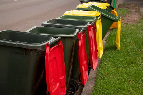 Genel olarak renkli kapaklı Avustralya çöp kutuları ve belediye çöpleri için kaldırım kenarındaki ev atıklarının geri dönüşümü