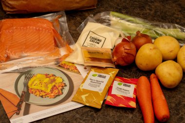 Sydney, Avustralya 2025-04-19 Hello Fresh yemek seti ve mutfak tezgahında yemek tarifi kartı. Yemek seti teslimat servisi.