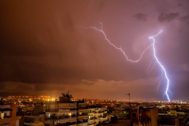 Yıldırım çarpması ile gece şehir manzarası. Şehirdeki fırtına sırasında güçlü bir gök gürültüsü. Buluttan yerdeki elektrik yıldırımına. Selanik, Kuzey Yunanistan