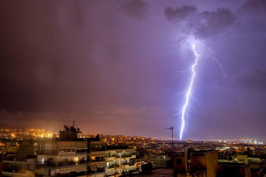 Yıldırım çarpması ile gece şehir manzarası. Şehirdeki fırtına sırasında güçlü bir gök gürültüsü. Buluttan yerdeki elektrik yıldırımına. Selanik, Kuzey Yunanistan