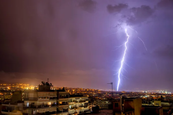 night city view under thunderstorm with strike of lightning. Powerful thunderbolt during thunderstorm in the city. Cloud to ground electric lightning behind. Thessaloniki, North Greece