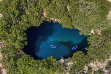 Kefalonia 'daki Melissani Mağarası kristal berrak suları olan çarpıcı bir yeraltı mağarası. Güneş ışığı açık tavandan akar, turkuaz gölü aydınlatır ve büyülü bir atmosfer yaratır.