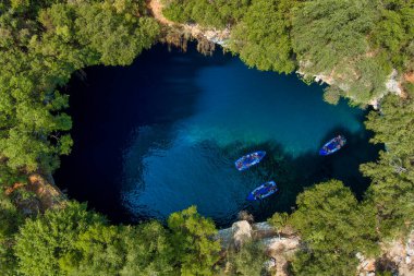 Kefalonia 'daki Melissani Mağarası kristal berrak suları olan çarpıcı bir yeraltı mağarası. Güneş ışığı açık tavandan akar, turkuaz gölü aydınlatır ve büyülü bir atmosfer yaratır.