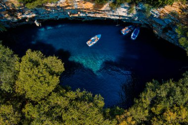 Kefalonia 'daki Melissani Mağarası kristal berrak suları olan çarpıcı bir yeraltı mağarası. Güneş ışığı açık tavandan akar, turkuaz gölü aydınlatır ve büyülü bir atmosfer yaratır.