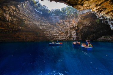 Kefalonia, Yunanistan - 25 Temmuz 2024: Kefalonya 'nın ünlü bir mücevheri olan Melissani Mağarası ve Göl, ziyaretçileri kristal berrak sularını tekneyle keşfetmeleri için ağırlayarak, şaşırtıcı bir ışık etkileşimi ortaya çıkardı.