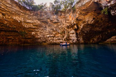 Kefalonia, Yunanistan - 25 Temmuz 2024: Kefalonya 'nın ünlü bir mücevheri olan Melissani Mağarası ve Göl, ziyaretçileri kristal berrak sularını tekneyle keşfetmeleri için ağırlayarak, şaşırtıcı bir ışık etkileşimi ortaya çıkardı.