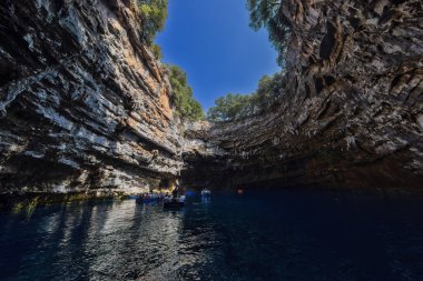 Kefalonia, Yunanistan - 25 Temmuz 2024: Kefalonya 'nın ünlü bir mücevheri olan Melissani Mağarası ve Göl, ziyaretçileri kristal berrak sularını tekneyle keşfetmeleri için ağırlayarak, şaşırtıcı bir ışık etkileşimi ortaya çıkardı.