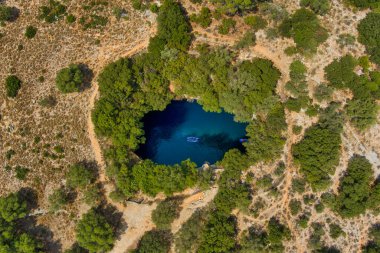 Kefalonia 'daki Melissani Mağarası kristal berrak suları olan çarpıcı bir yeraltı mağarası. Güneş ışığı açık tavandan akar, turkuaz gölü aydınlatır ve büyülü bir atmosfer yaratır.