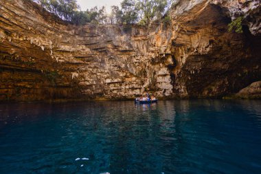 Kefalonia, Yunanistan - 25 Temmuz 2024: Kefalonya 'nın ünlü bir mücevheri olan Melissani Mağarası ve Göl, ziyaretçileri kristal berrak sularını tekneyle keşfetmeleri için ağırlayarak, şaşırtıcı bir ışık etkileşimi ortaya çıkardı.