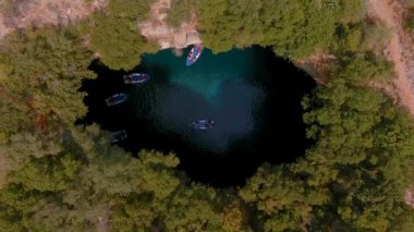 Kefalonia 'daki Melissani Mağarası kristal berrak suları olan çarpıcı bir yeraltı mağarası. Güneş ışığı açık tavandan akar, turkuaz gölü aydınlatır ve büyülü bir atmosfer yaratır.