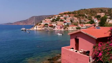 Assos, Kefalonia, Yunanistan. Gökyüzü İyon Denizi ile çevrili, manzaralı bir yarımadada yuva yapmış pitoresk bir köy. Renkli evleri ve sakin hangarları, mükemmel bir kartpostal ayarı yaratıyor..