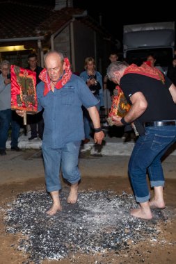 Lagadas, Yunanistan 23 Mayıs 2023: Anastenaria ayini sırasında inananlar, inancın, arındırmanın ve geleneğin sembolü olarak dini simgeler ve kırmızı bezlerle yanan kömürlerin üzerinde yalınayak yürürler.