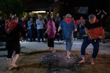 Lagadas, Yunanistan 23 Mayıs 2023: Anastenaria ayini sırasında inananlar, inancın, arındırmanın ve geleneğin sembolü olarak dini simgeler ve kırmızı bezlerle yanan kömürlerin üzerinde yalınayak yürürler.