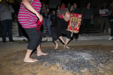 Lagadas, Yunanistan 23 Mayıs 2023: Anastenaria ayini sırasında inananlar, inancın, arındırmanın ve geleneğin sembolü olarak dini simgeler ve kırmızı bezlerle yanan kömürlerin üzerinde yalınayak yürürler.