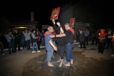 Lagadas, Yunanistan 23 Mayıs 2023: Anastenaria ayini sırasında inananlar, inancın, arındırmanın ve geleneğin sembolü olarak dini simgeler ve kırmızı bezlerle yanan kömürlerin üzerinde yalınayak yürürler.